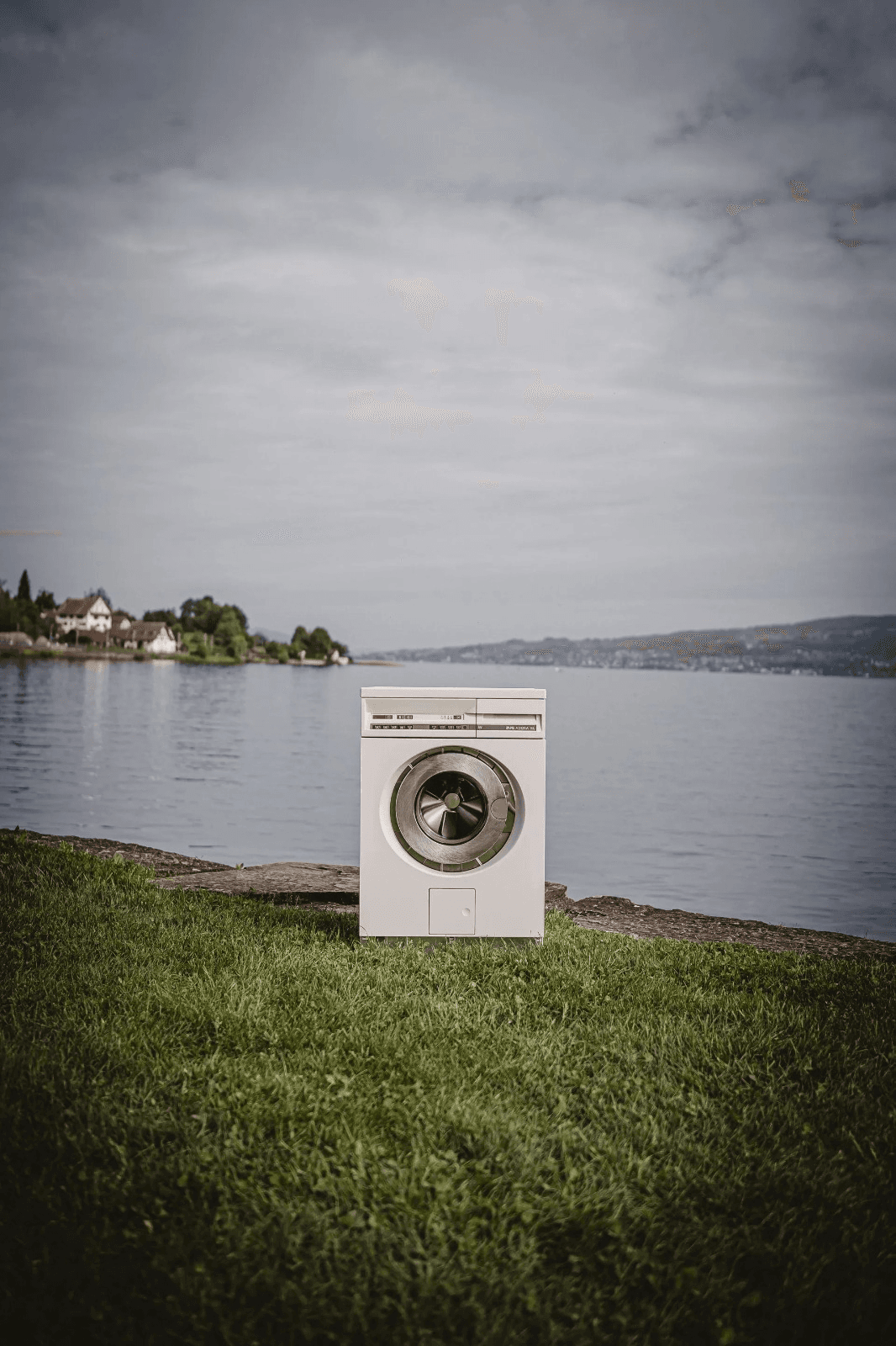 Washing machine on a grassy shore next to a lake